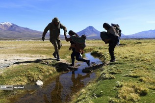 کمک یک سرباز شیلیایی به یک مهاجر درعبور از کانال آبی در نزدیکی کولچان شیلی