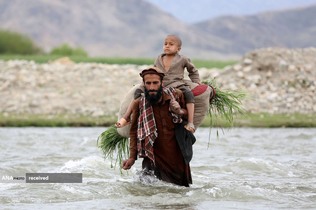 عبور کشاورز افغان با پسرش از رودخانه ای در شهر محترلم استان لغمان، افغانستان