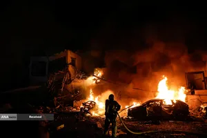 یک آتش نشان اسرائیلی برای خاموش کردن آتش در یک خودرو در محل برخورد پرتابه پس از پرتاب موشک های ایران به اسرائیل، در تل آویو کار می کند