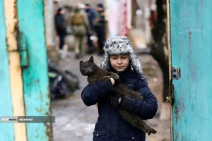 کودک اوکراینی در حال خارج کردن گربه خود از درگیری منطقه دونتسک